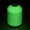 Biała nić do haftu Simthread Glow, 1000 m – zielona poświata nici po naświetleniu, na ciemnym tle.
